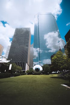 引人注目的城市景观包括高耸的摩天大楼、蓝天，以及城市公园中的大型眼球雕塑