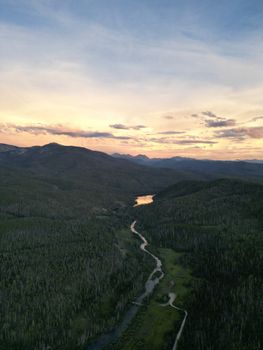 Scenic aerial view of Grand Lake at sunset showcasing forests, mountains, and meandering river.