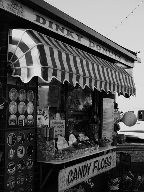 A nostalgic street vendor with candy floss and donuts in a black and white setting.