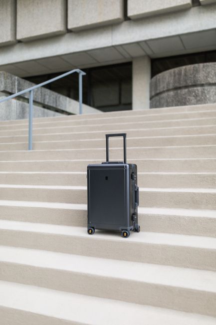 A sleek modern suitcase positioned on concrete steps outside a building in Greensboro, NC.
