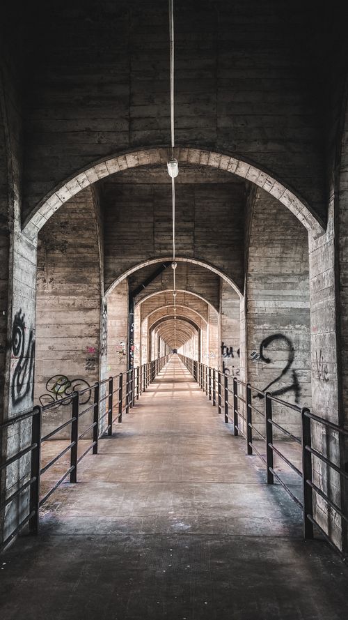 Free A narrow, dimly-lit, graffiti-covered corridor with a tunnel-like perspective. Stock Photo