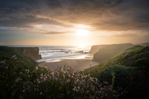 Free A stunning coastal landscape at golden hour with dramatic cliffs and a vibrant sunset over the ocean. Stock Photo
