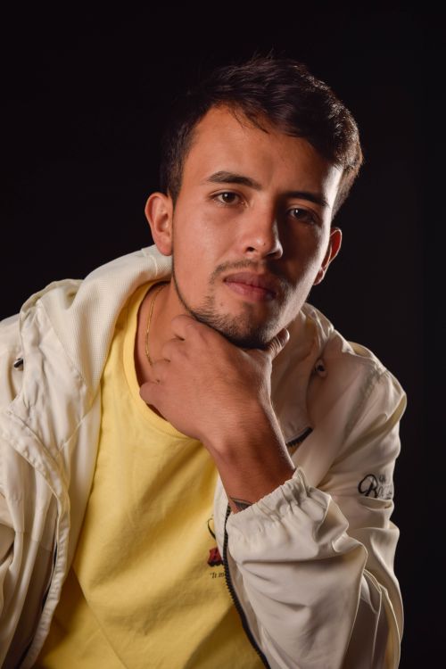 Free Close-up portrait of a serious young man in a white jacket with a black background. Stock Photo