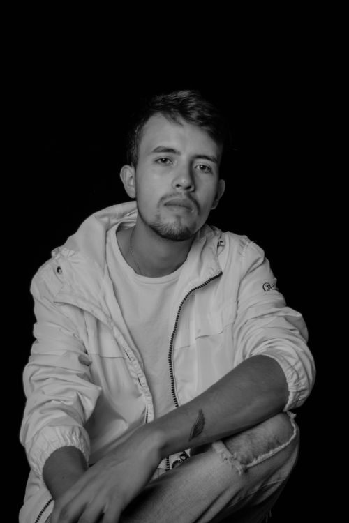 Free Stunning black and white portrait of a thoughtful young man in a white jacket, showcasing modern style. Stock Photo