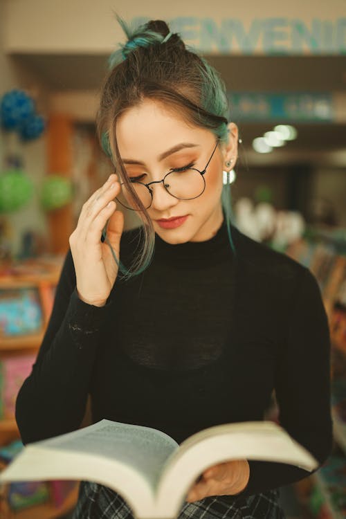 A Woman Wearing Eyeglasses While Reading a Book