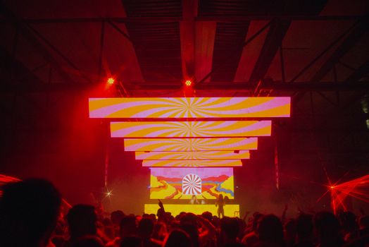Energetic nightclub scene with colorful LED displays and dancing crowd.