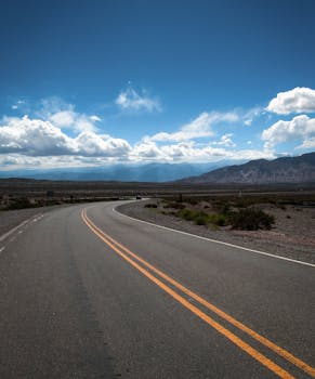 A winding road under a vibrant blue sky and clouds in Salta, Argentina.
