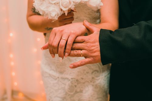 Free A close-up of bride and groom's hands showing wedding rings and floral bouquet. Stock Photo