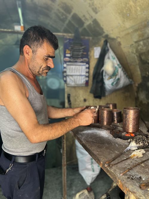 Free A craftsman working on metal cups in an artisan workshop. Warm natural lighting. Stock Photo