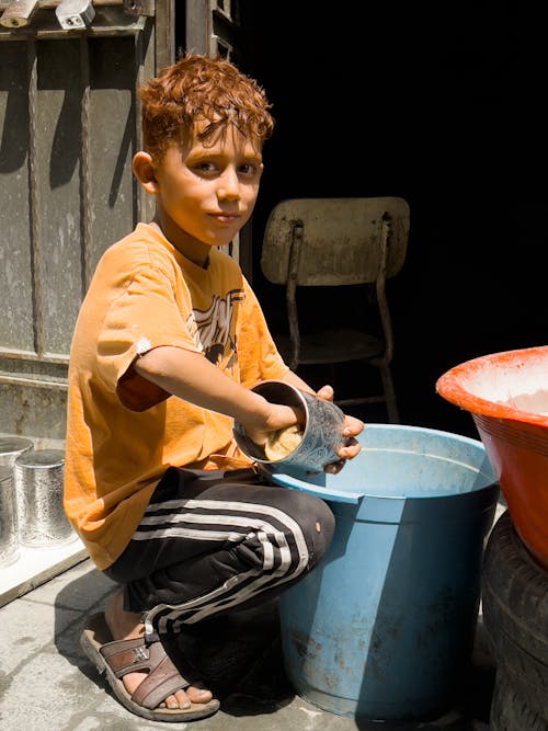 A Boy Washing a Metal Cup