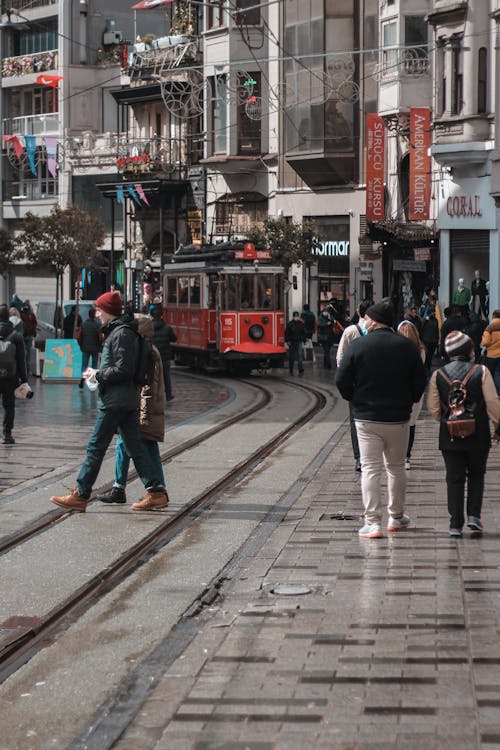 People Walking on the Street Near the Red Tram