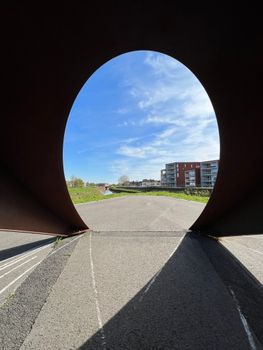 A vibrant urban scene viewed through an artistic tunnel, under a bright blue sky in Lier, Belgium. — photo by Jelena Sanader