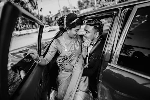 Photo of a Romantic Couple Elegantly Dressed Cuddling in a Car