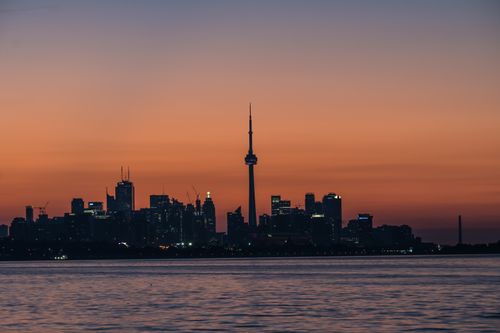 Free Stunning silhouette of Toronto skyline and CN Tower during sunset over Lake Ontario. Stock Photo