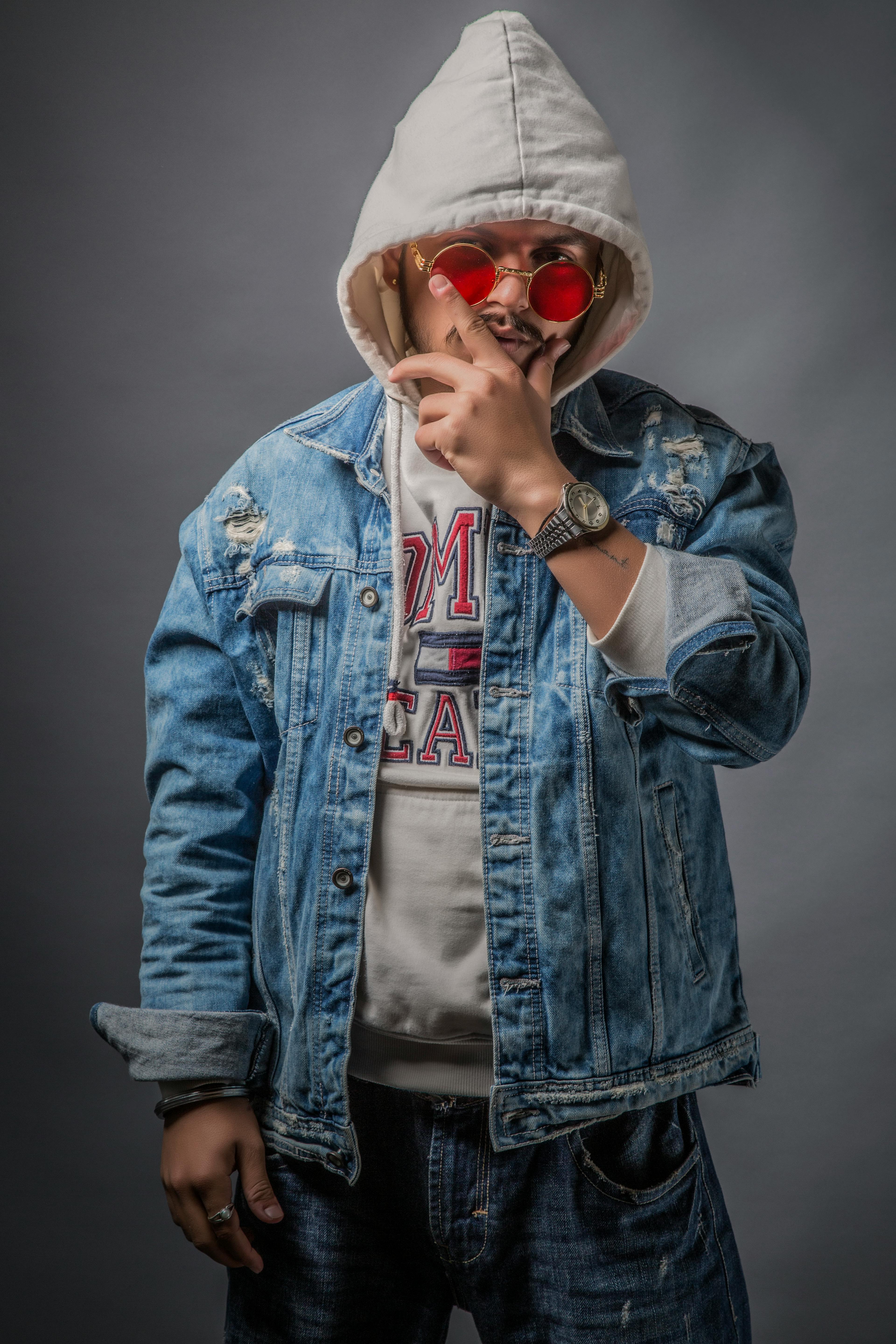 Fashionable adult wearing a denim jacket, hoodie, and red sunglasses in Chandigarh, India.