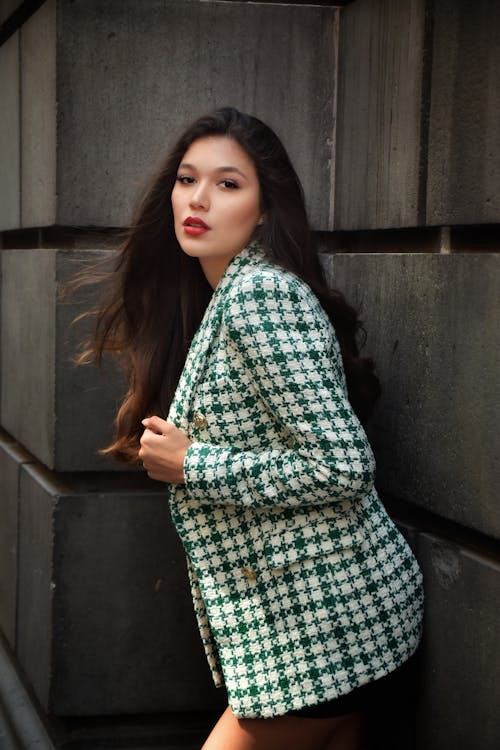 Woman in Plaid Blazer Leaning on a Stone Wall