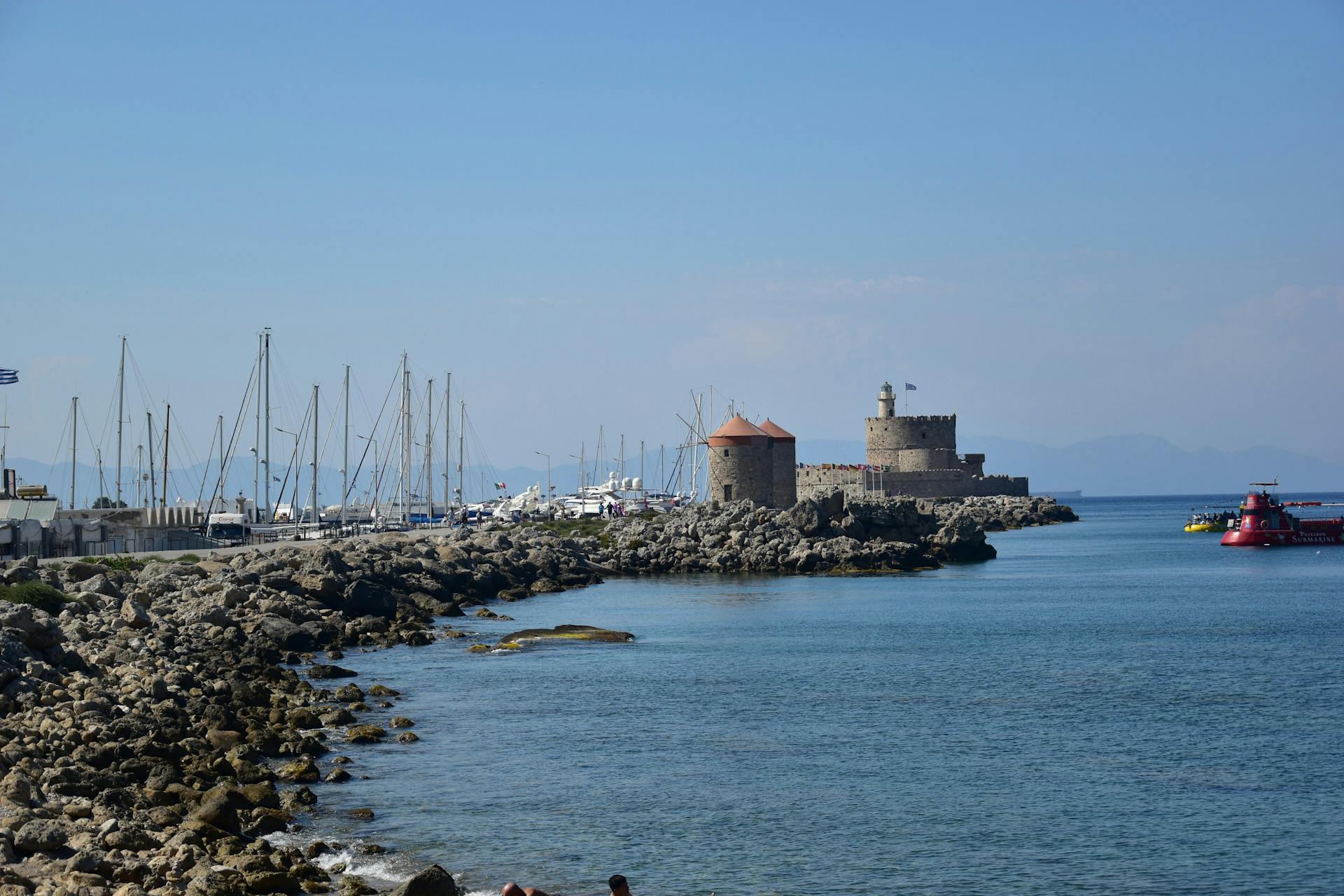 Scenic view of Saint Nicholas Fortress and marina on the rocky coast of Rhodes, Greece.