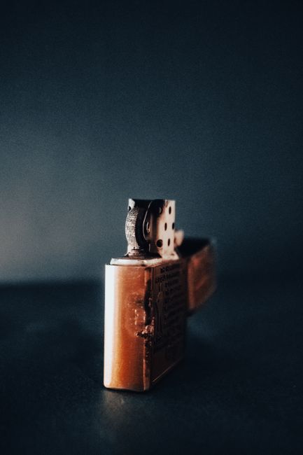 Close-up of a vintage brass lighter with a dramatic, moody background.