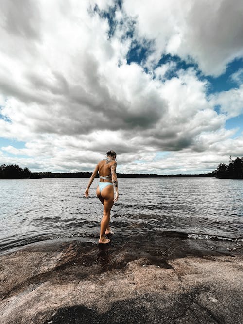A Tattooed Woman in White Bikini Standing on Sea Shore
