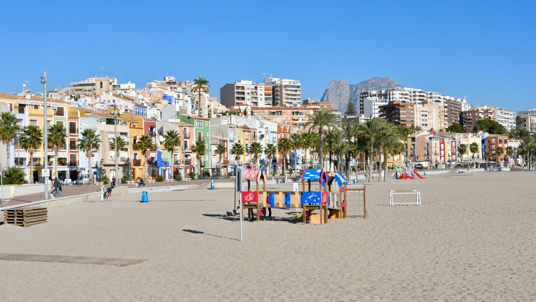 Scenic view of vibrant buildings and sandy beach in Villajoyosa, Spain on a sunny day.