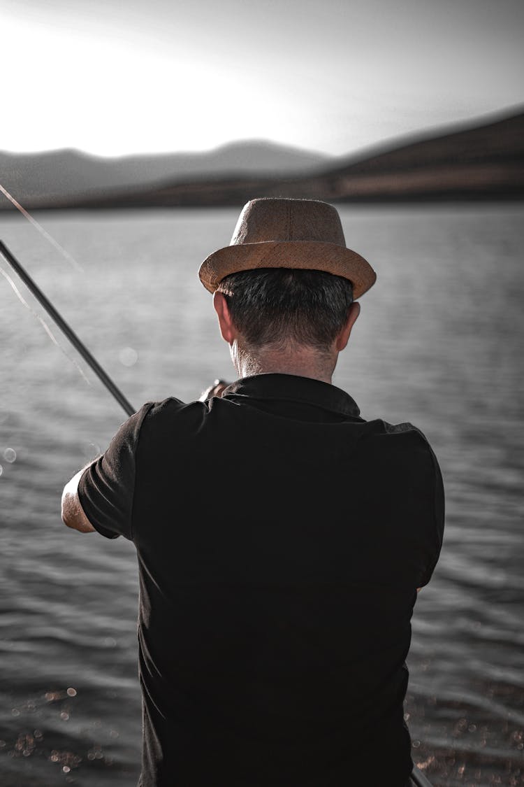 A Back View Of A Man In Black Shirt Holding A Fishing Rod