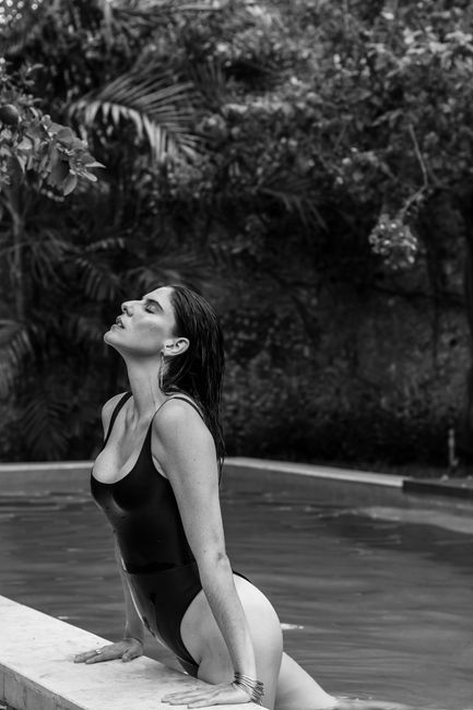 Black and white portrait of a woman in a swimsuit by a pool in Mérida, showcasing elegance and relaxation.