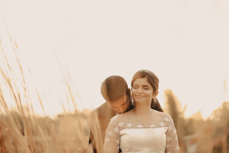 A Man Kissing The Bride On Shoulder