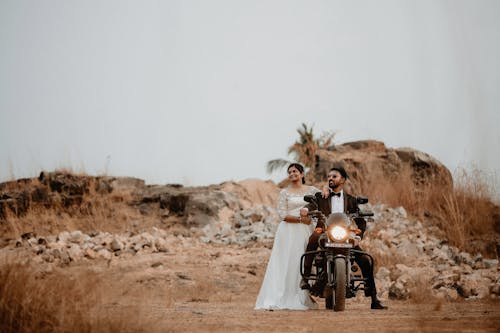 Woman in Wedding Dress with Man in Wedding Suit on Motorcycle