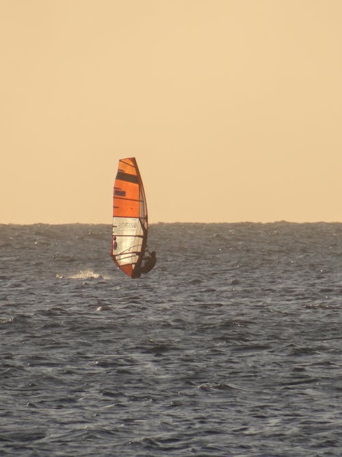 A Person Windsurfing on the Sea Under Golden Sky