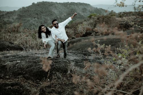 Man and Woman in White Long Sleeve Shirts Having Fun Together Standing in a Forest