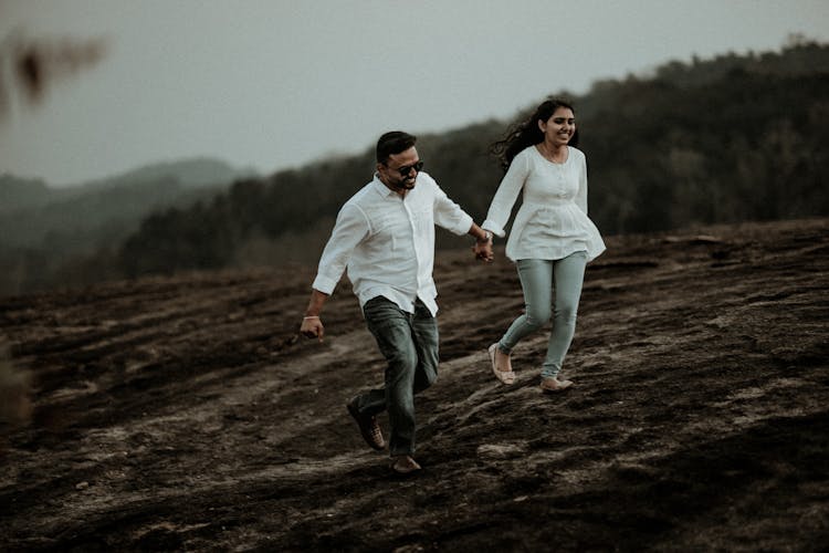 A Couple Holding Hands While Running