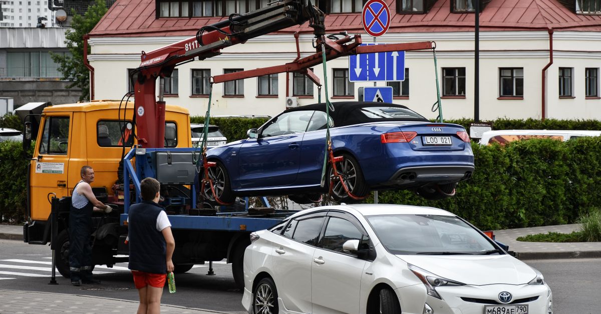Towing a blue Audi convertible in a bustling city street.