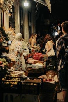 A lively night market scene with vendors and shoppers under warm urban lighting.