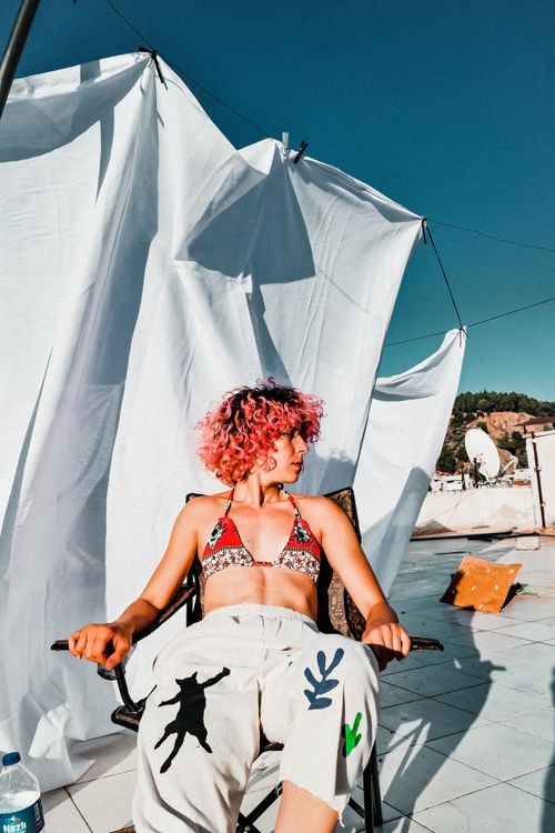 Free Woman in bikini top relaxing on rooftop. Vibrant summer vibes with colorful fashion. Stock Photo