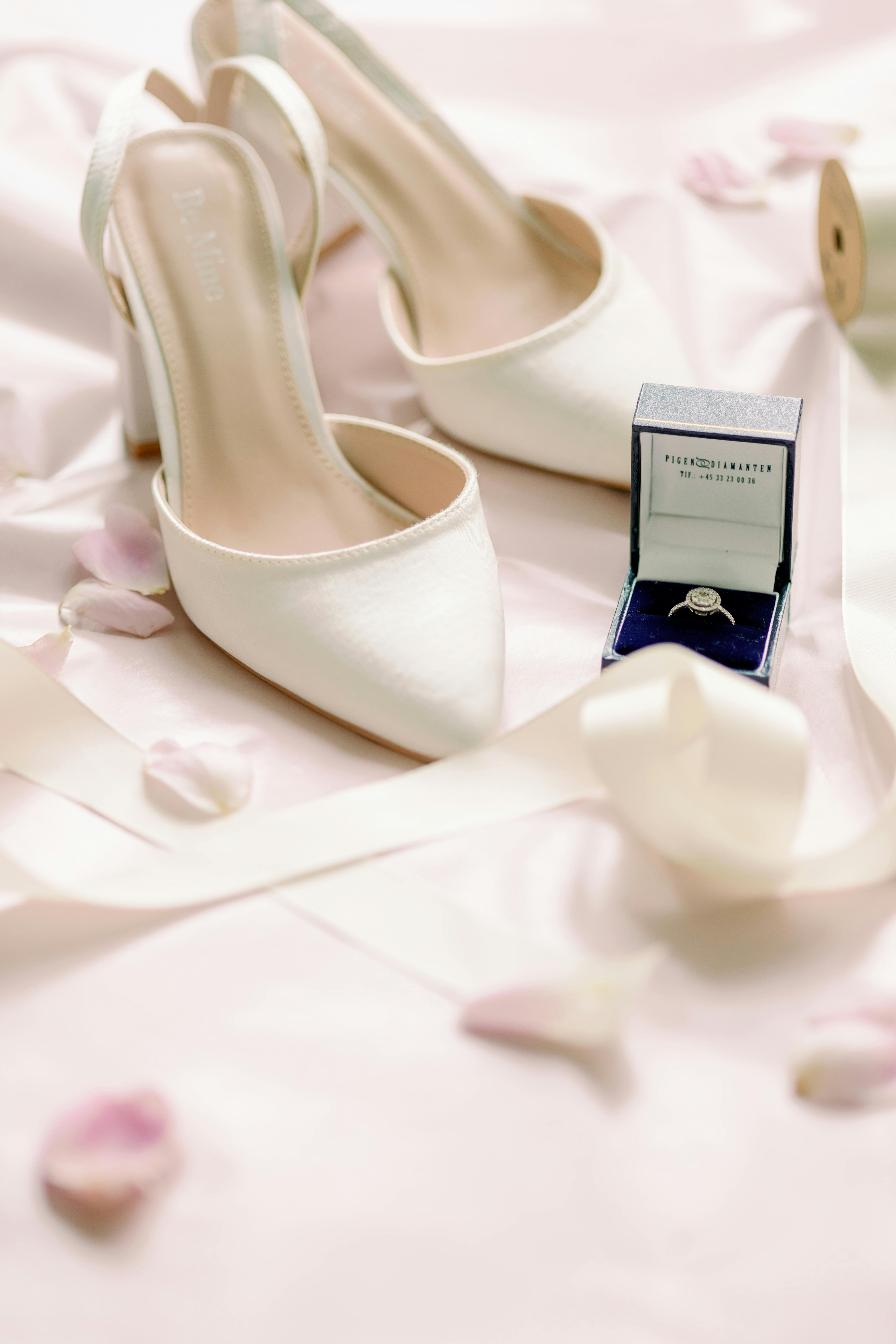 Close-up of elegant bridal shoes and a diamond ring for a wedding setting.