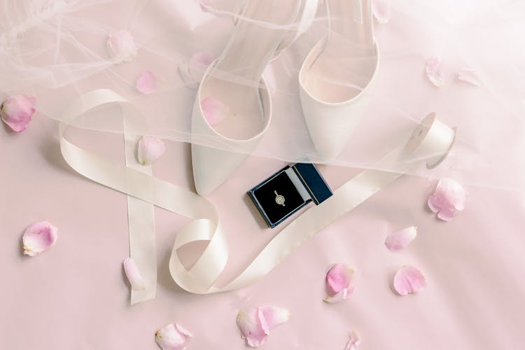 White High Heels And A Box With Diamond Ring On A Pink Surface