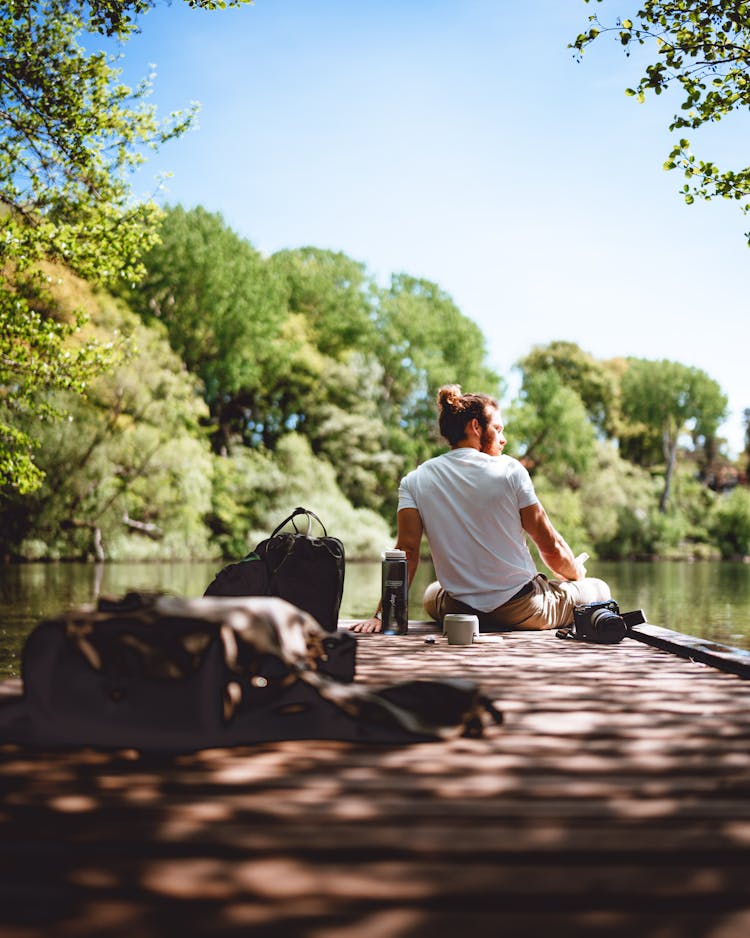 Man Sitting On Pier On River