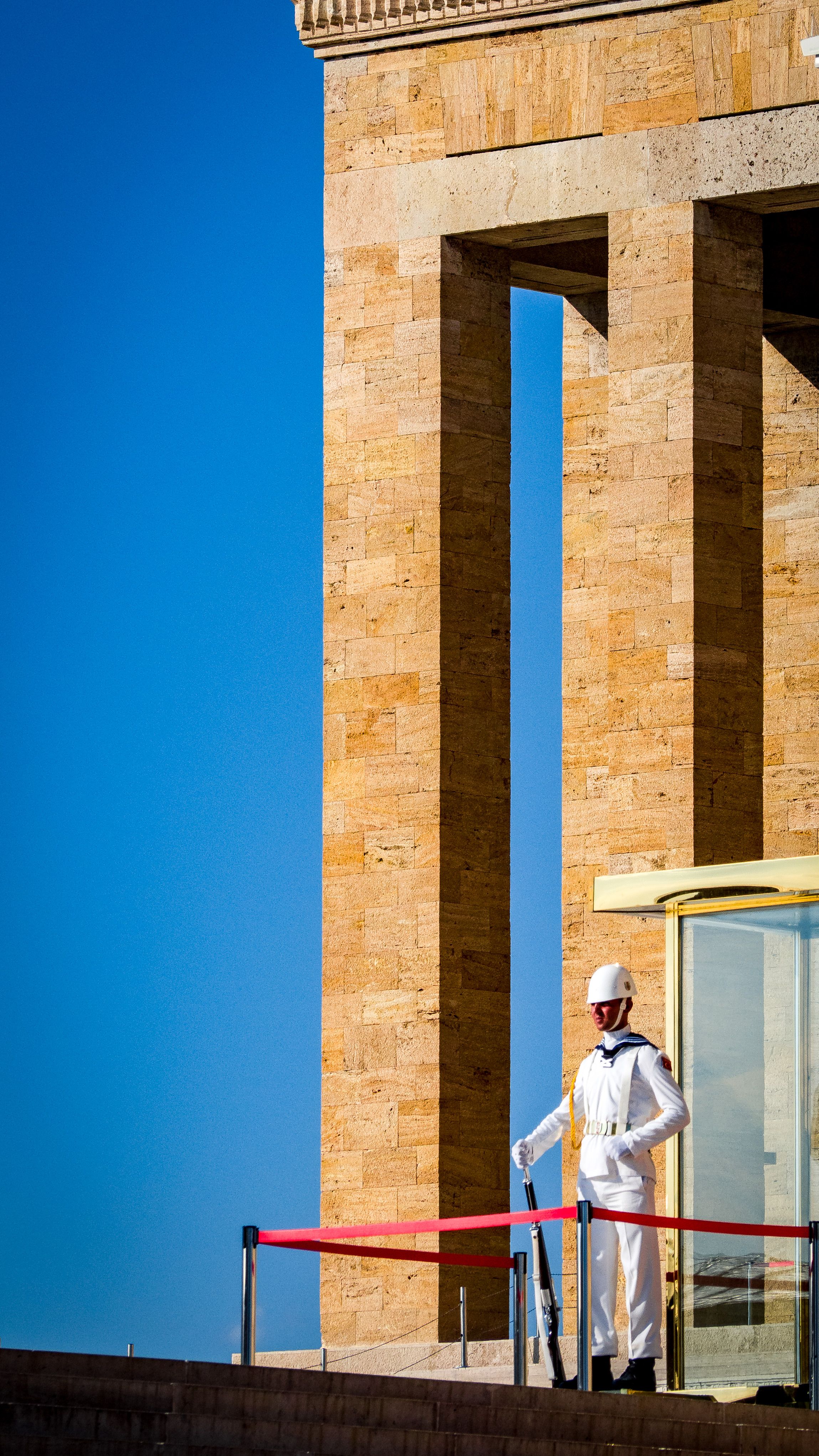 A guard stands at Anıtkabir, the mausoleum of Mustafa Kemal Atatürk, under a clear blue sky.