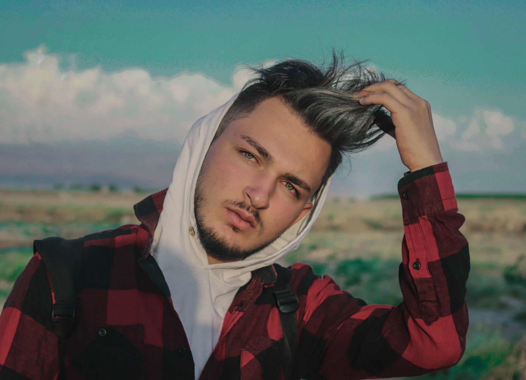 Homme en chemise à carreaux rouge et noir portée ouverte sur un hoodie blanc, look grunge homme streetwear