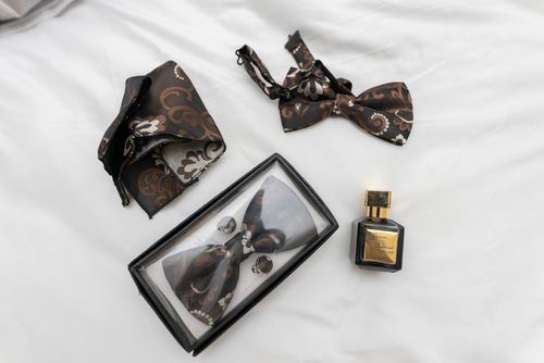 Free Stylish bow tie and perfume set on white fabric, capturing elegance and sophistication. Stock Photo