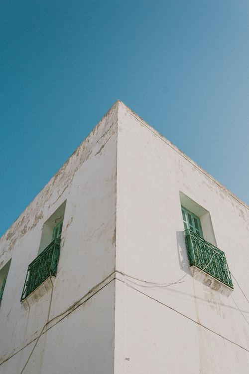 Free Low-angle view of a concrete building with green balconies under a clear blue sky. Stock Photo