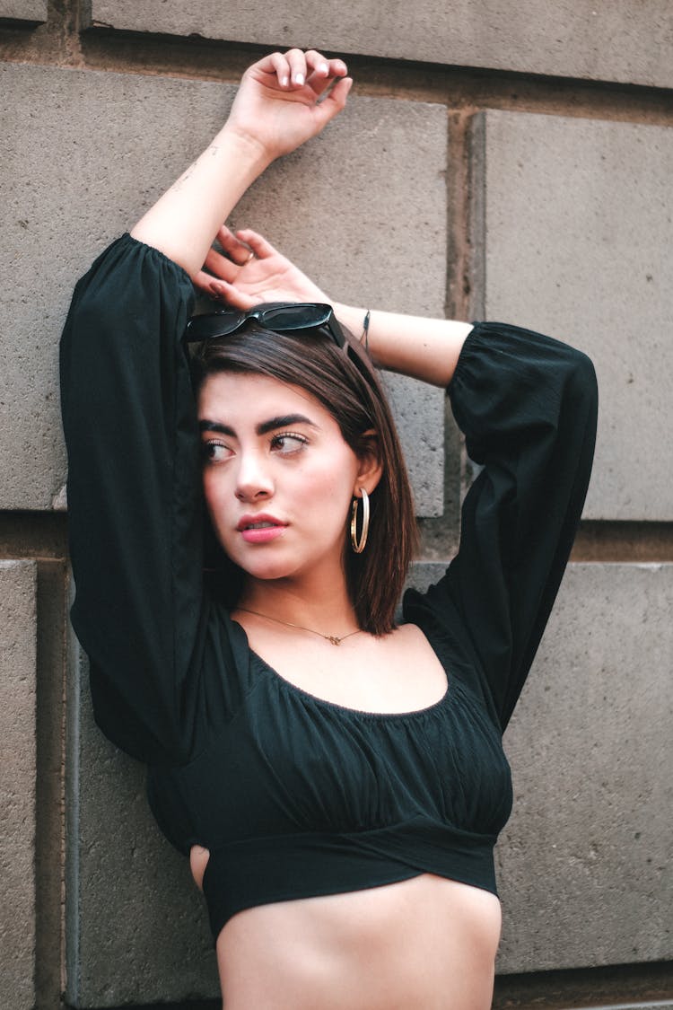 Woman Leaning Against Wall With Arms Raised Above Head