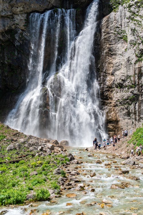 People Standing and Sightseeing Near Waterfalls