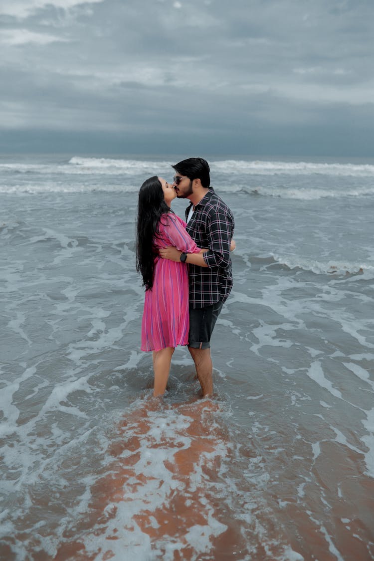 Man And Woman Standing On Beach And Kissing