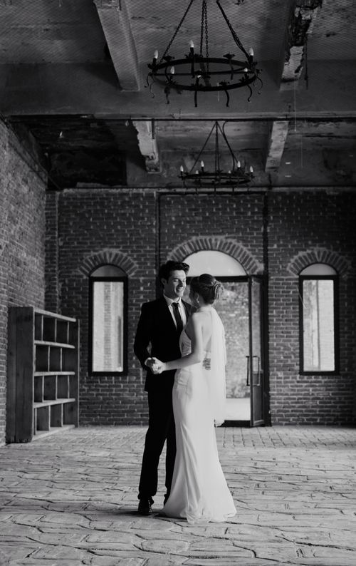 Free Black-and-white photo of a couple at an industrial wedding venue, embracing romantically. Stock Photo