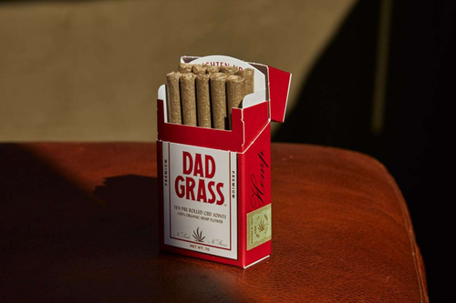 Free Red box of Dad Grass CBD joints displayed on a brown leather background. Stock Photo