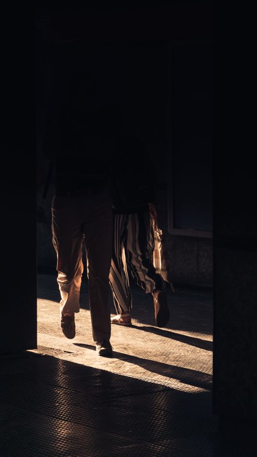 Free Two silhouetted figures walking through a corridor with dramatic lighting and shadows. Stock Photo