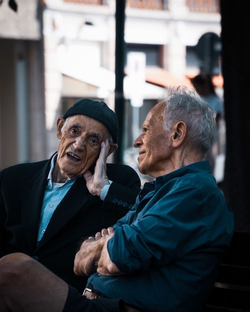 Free Two senior men sitting and talking on a bench in Milan, Italy, showing companionship. Stock Photo