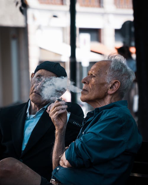 A Man in Blue Dress Long Sleeves Smoking a Tobacco