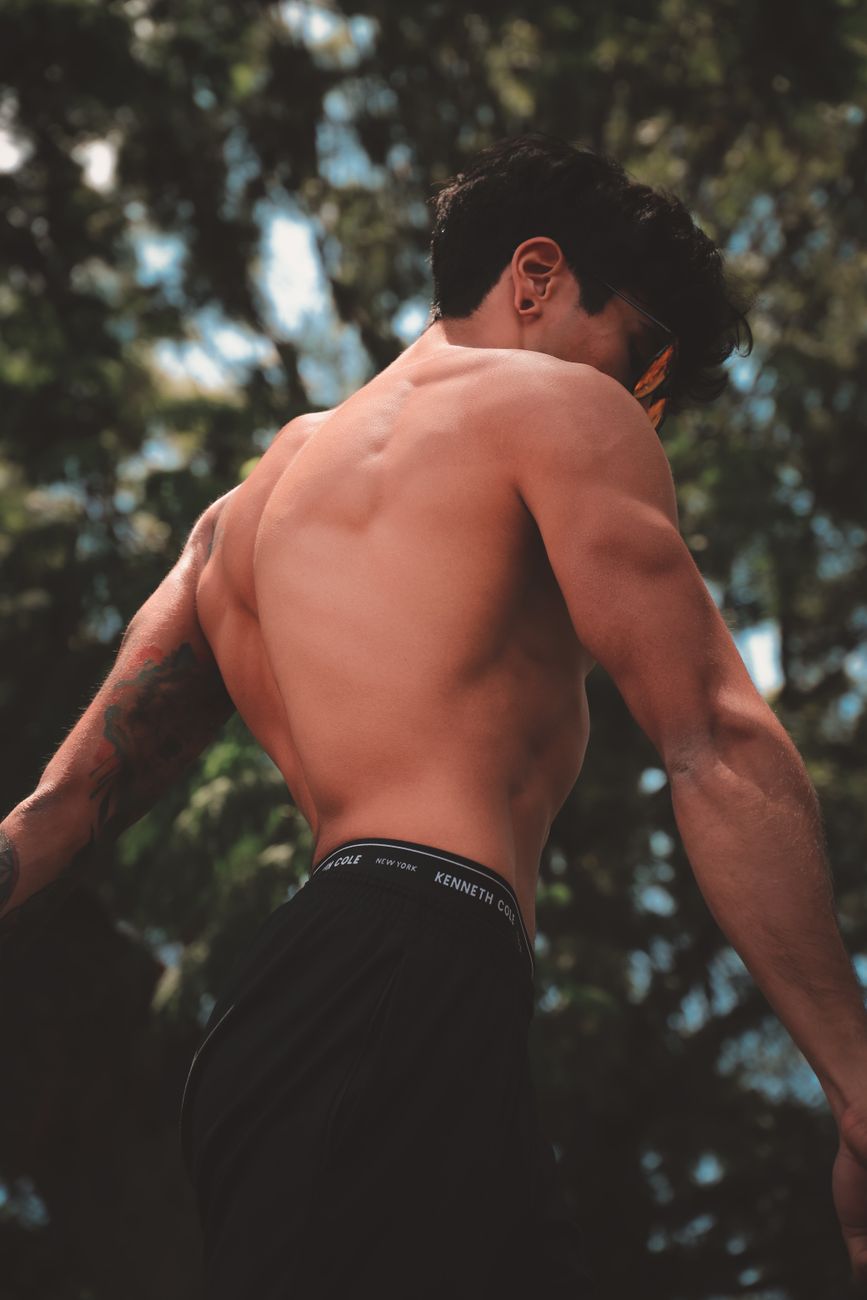 Shirtless man posing outdoors with muscular back in Mexico City park.